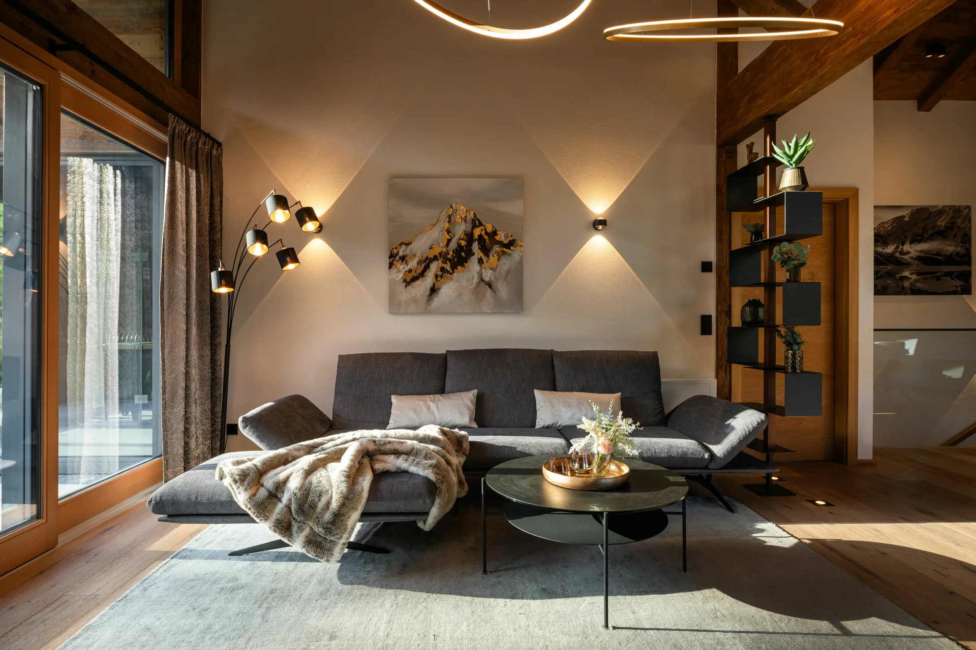 Warm beleuchteter Wohnbereich im DasKöniglich mit Sofa, Kuscheldecke und alpinen Details
