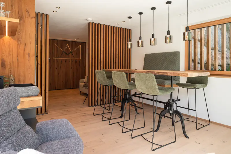 Essbereich mit Holztisch und grünen Barhockern