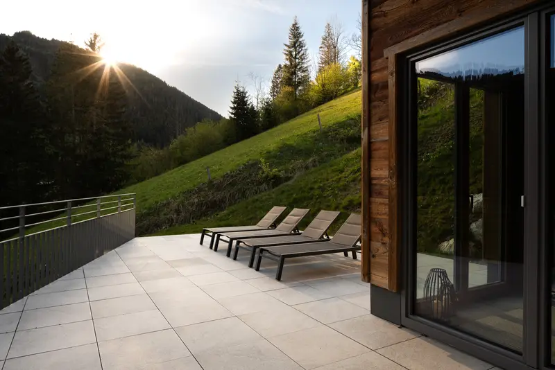 Terrasse mit Liegestühlen und Bergblick bei Sonnenuntergang