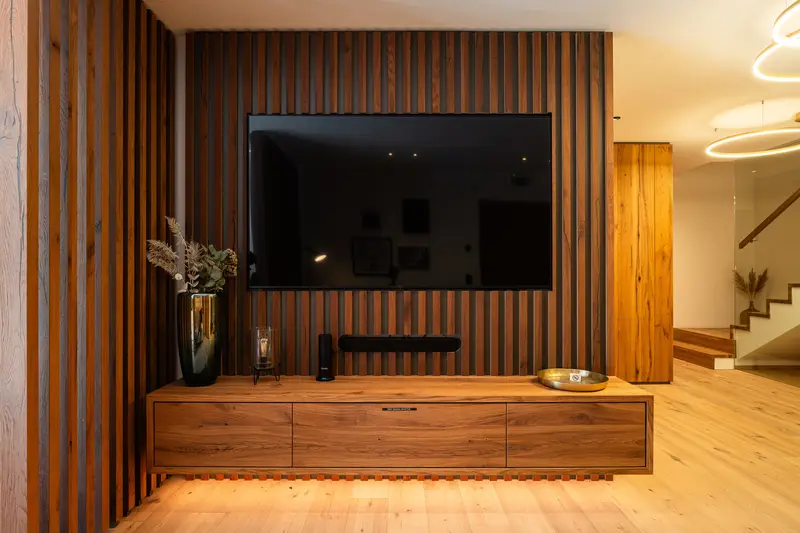 Fernseher an Holzlamellenwand über schwebendem Holzschrank