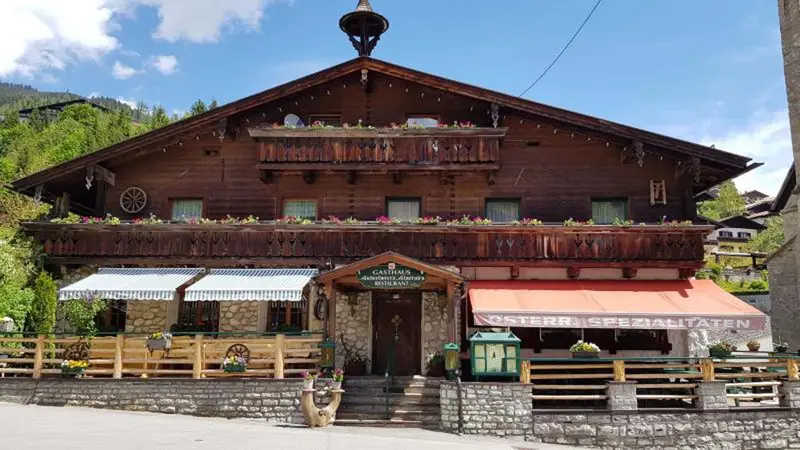 Gasthof mit Holzfassade und Sonnenterrasse in den Bergen