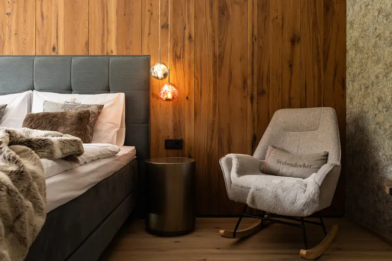 Schlafzimmer mit Holzwand und Schaukelstuhl