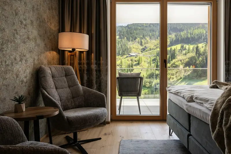 Coin salon avec fauteuil et vue sur le balcon et les montagnes