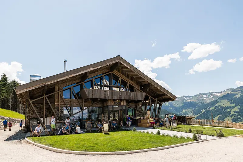 Holz-Restaurant in Berglandschaft mit Gästen auf der Terrasse