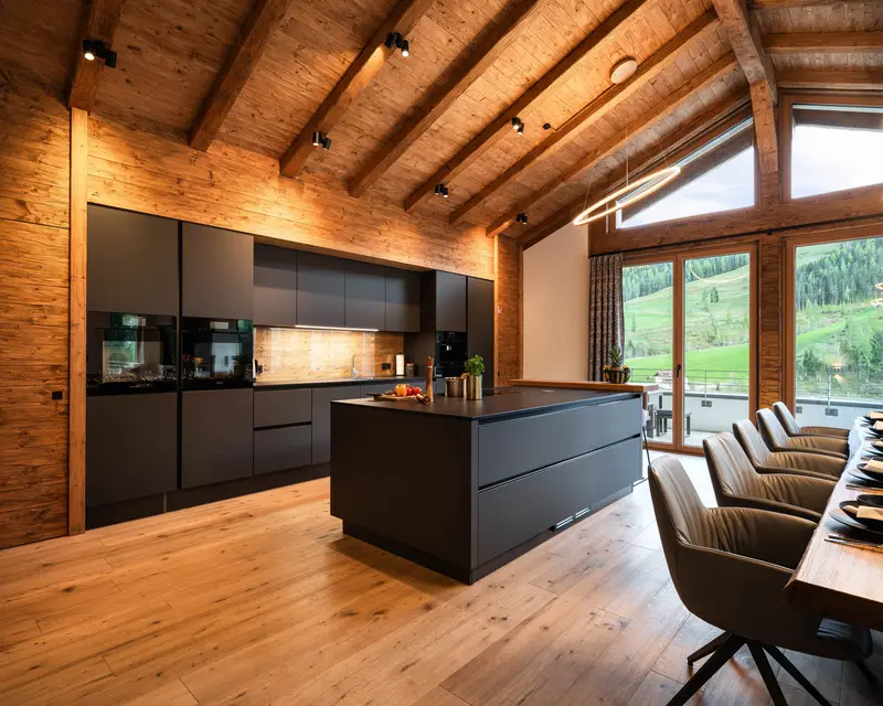 Moderne Chalet-Küche mit dunkler Kochinsel und Holzbalken