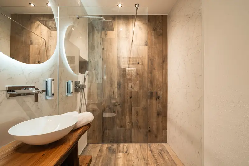 Salle de bains attenante avec douche habillée de bois et vasque sur plan en bois