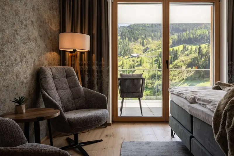 Zimmer mit Sessel und Bergblick vom Balkon
