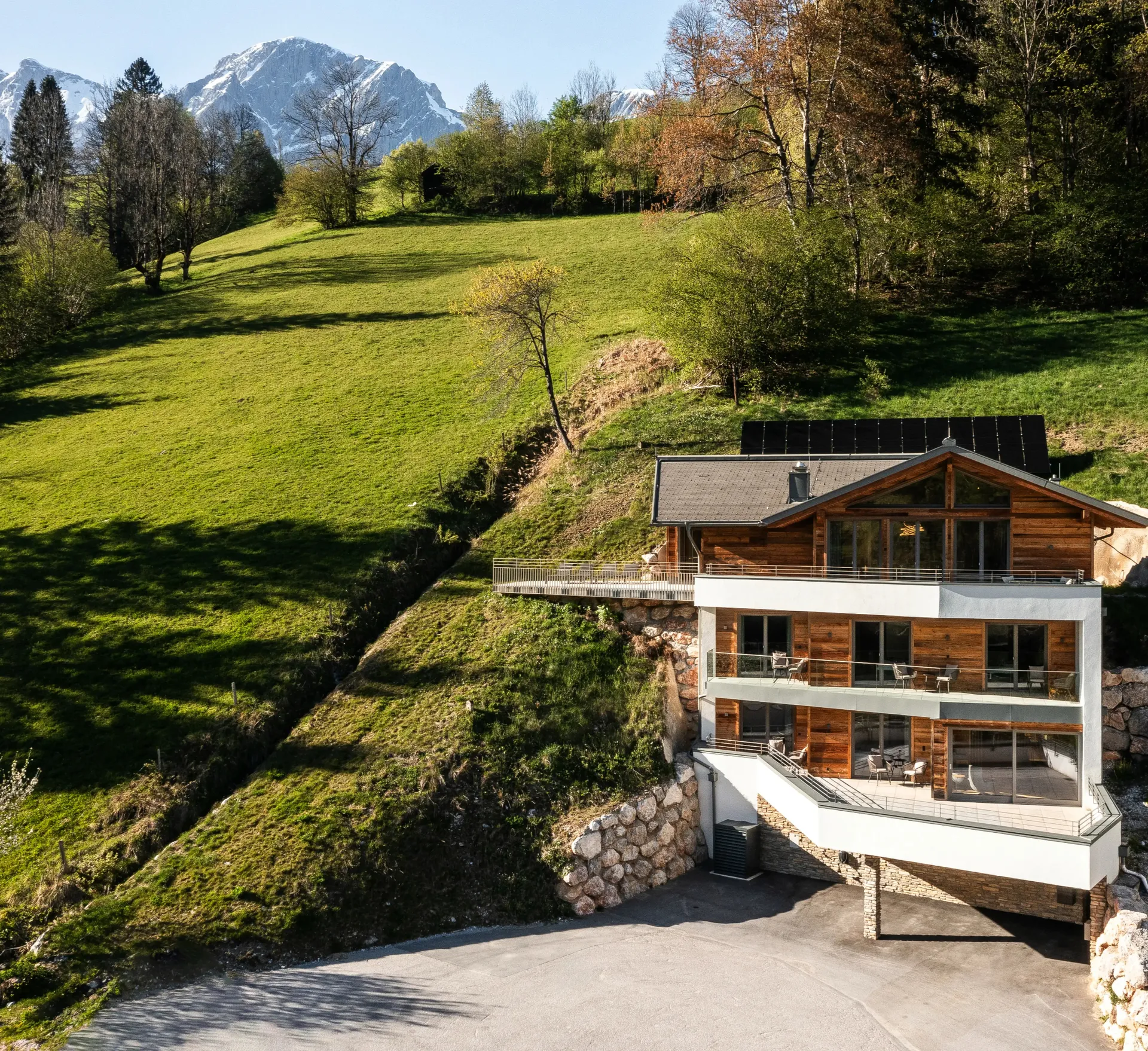 Das Chalet DasKöniglich am Hang mit grünen Wiesen und Bergpanorama im Sommer