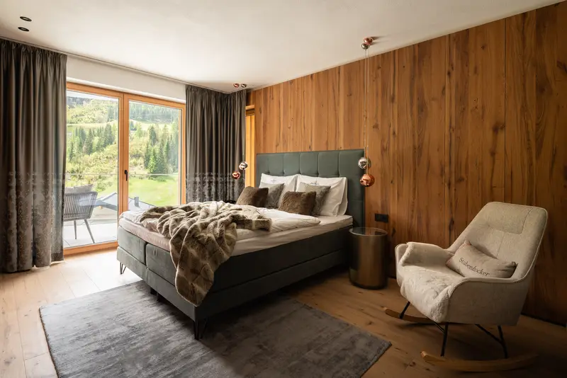 Chambre avec lit, mur en bois et vue sur la nature