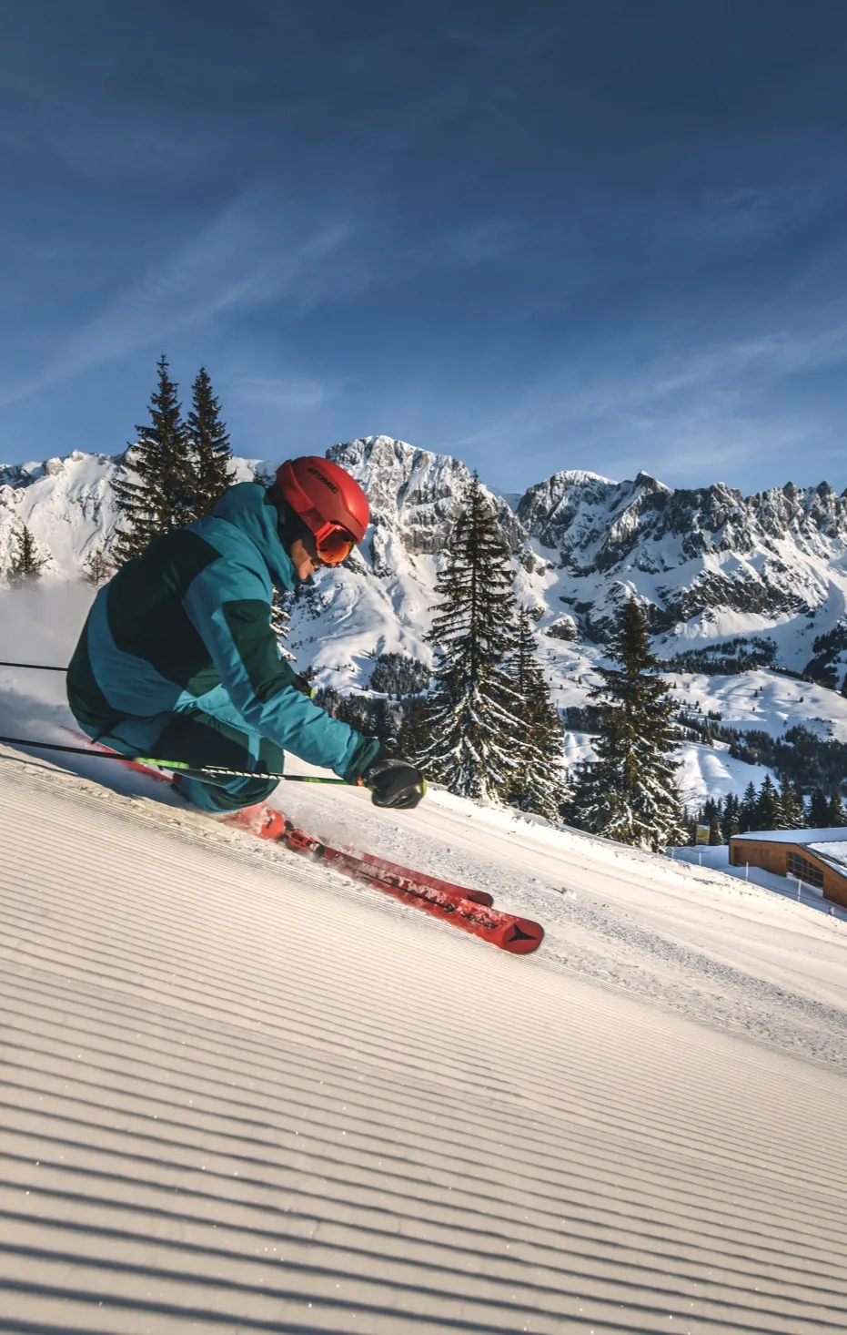 Skifahrer im Schwung auf frisch präparierter Piste vor dem Hochkönig-Massiv