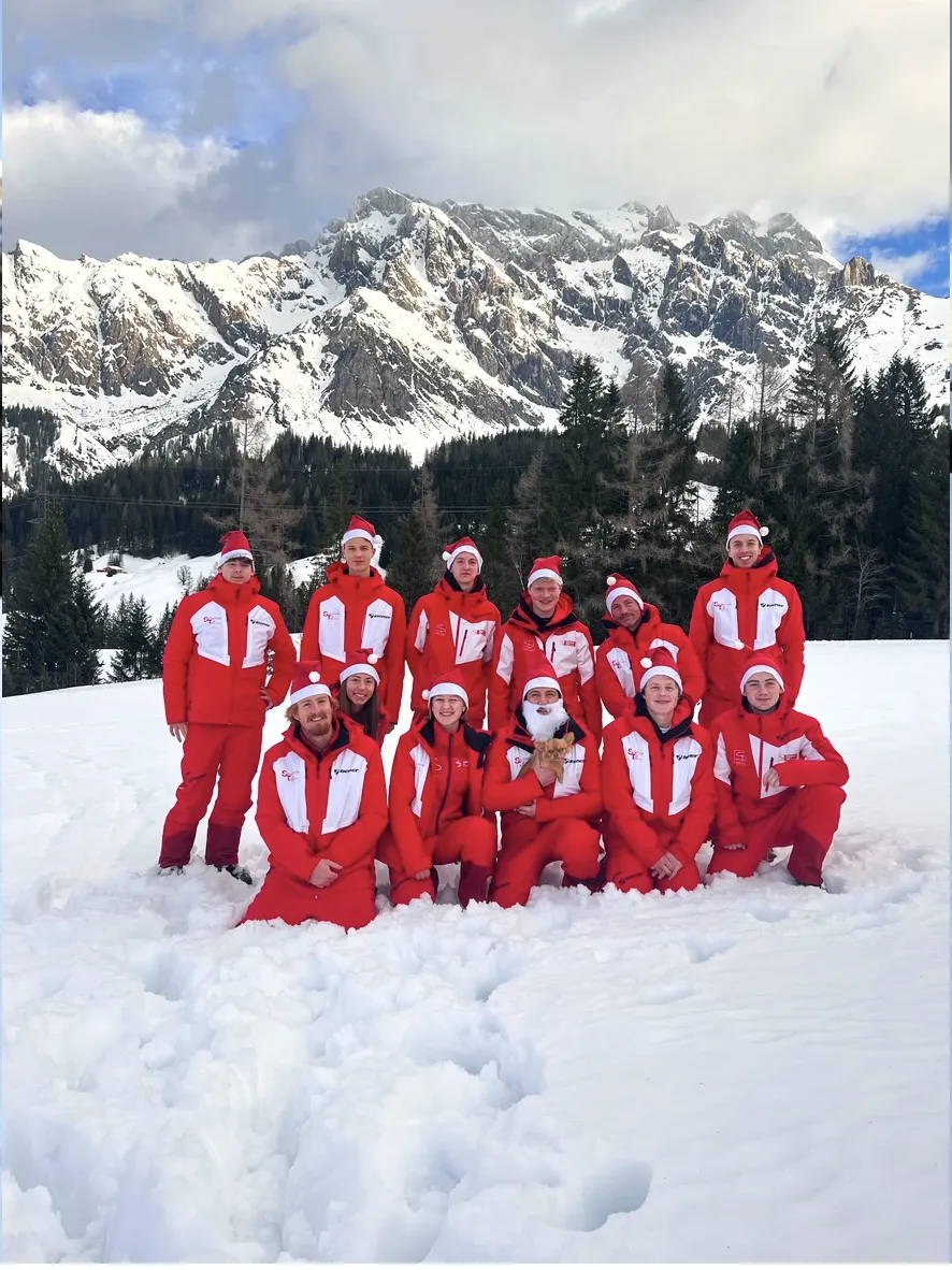Skilehrer-Team der Skischule Top Dienten in roten Anzügen im verschneiten Gebirge